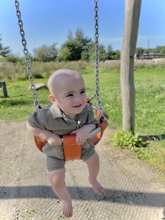 a baby is smiling and playing on a swing