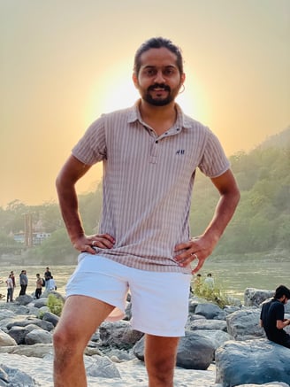 a man standing on a rocky beach with a sunset in the background