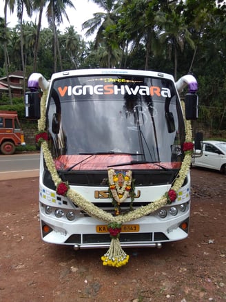 A white color bus with name and decorated by flowers.