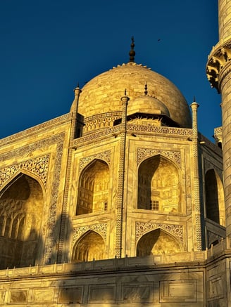 White, pristine marble of the Taj Mahal reflecting the hue of gold as the Sun begins to shine