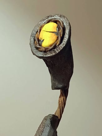 Close up of a semi circular, linear sculpture, painted bronze with yellow detail, on yew plinth.