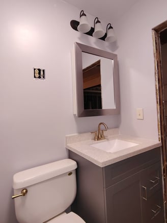 Bathroom remodeling in Goshen, IN with new toilet, new sink, new mirror, and new lighting.