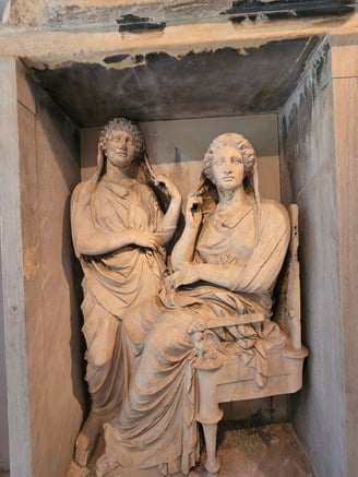 two ancient Greek statues of women, displayed in a museum in Athens