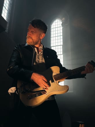a man in a leather jacket playing guitar