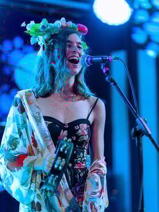 a woman in a floral dress singing into a microphone