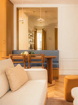 Vue du salon et coin repas avec miroir sur mesure vieilli dans un appartement haussmannien à Paris
