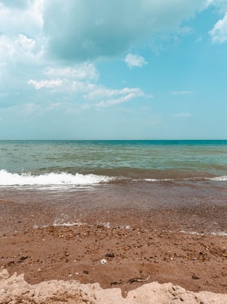 Serene Lake Michigan shoreline with calm waves, sandy beach, and blue skies, reflecting the tranquil essence of Lakeside Yin.