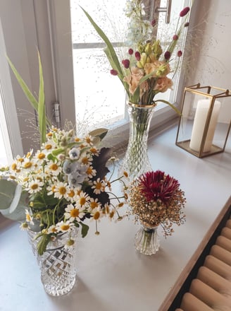 Goldene Laterne und blau orangene Blumen in Vasen auf einer Fensterbank 