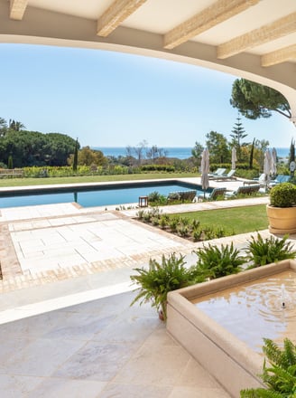 View from the shaded porch across the pool, with the Mediterranean Sea visible in the background.