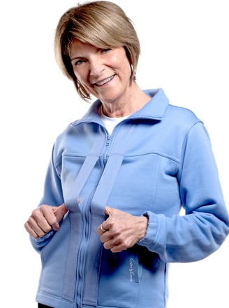 Smiling blonde model wearing blue Easeability Jacket with thumbs in front handles
