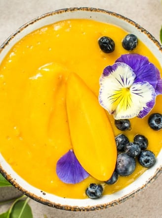 a bowl of african mango and flowers on a table