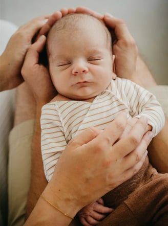 Bébé endormi dans les mains de ses parents – photo naissance à domicile Gard