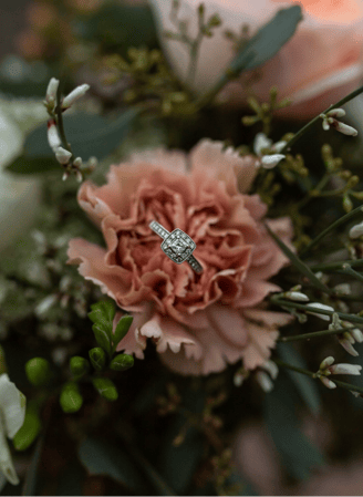 a diamond ring with a diamond ring on top of a bouquet of flowers