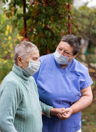Socio sanitario ayudando a persona mayor a andar con mascar