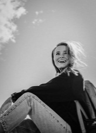 black and white photo of a young explorer woman sitting outdoors and smiling