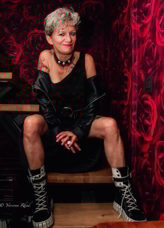 Portrait d'une femme élégante assise sur un tabouret dans un décor rouge par Yveophoto