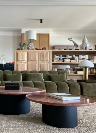 Contemporary lounge at Villa La Gratitud with velvet sofas, round marble tables, and bookshelves.