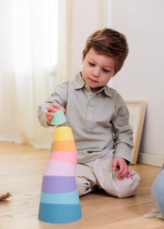 The boy building a tower from colorful stacking rings.