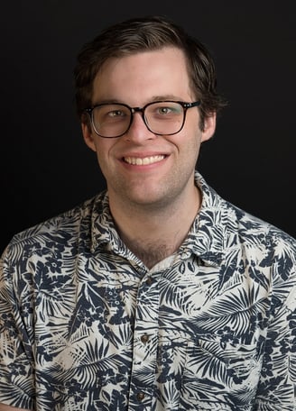 a man in a blue shirt and glasses with big smile