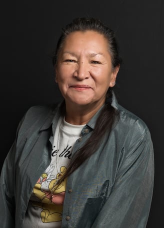 a female Native American with long hair and necklace smiling