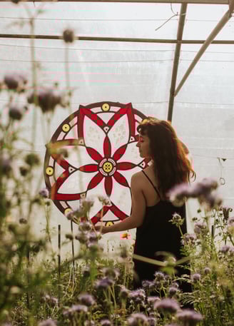 Artiste tenant son oeuvre dans ses bras. Rosace en vitrail écologique au milieu de fleurs sauvages