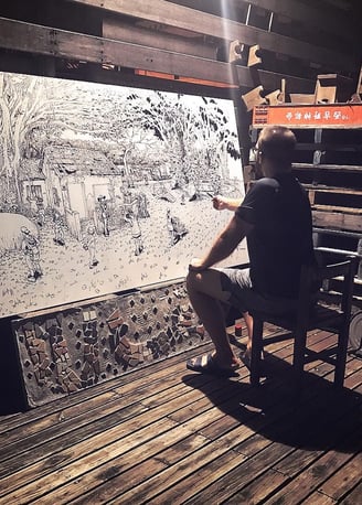 Artist Gene Bond drawing large-scale mural with acrylic marker on outdoor board in Taiwan.