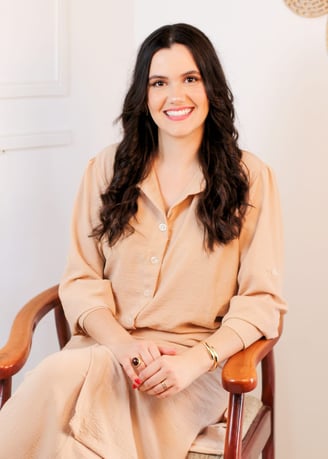 a woman in a tan dress sitting in a chair