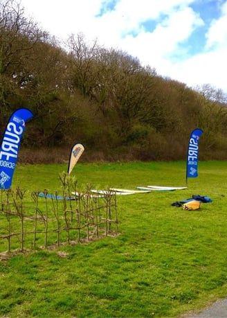 Surfboards laid on grass with surf school teardop flags