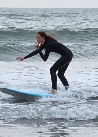 A female surfer riding a baby blue surfboard and a small broken wave.