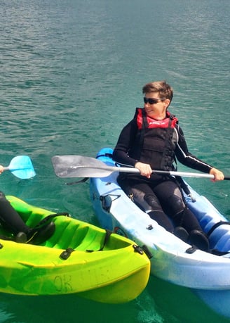 Two kayakers side by side with deep green sea