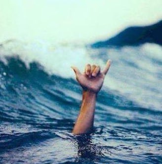 A hand coming out of the sea making a shaka