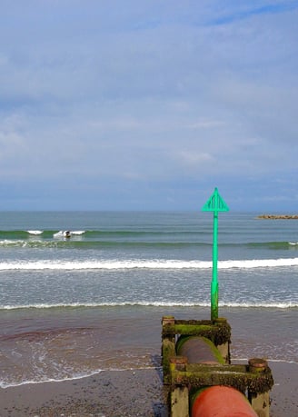 Clean waves in Borth with a longboarder riding one with blue skies