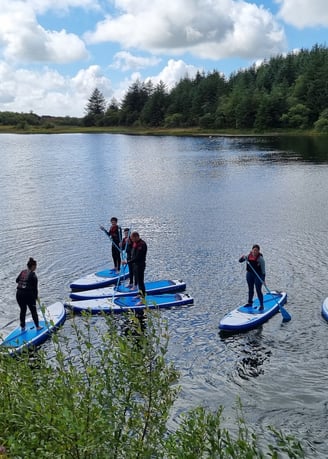 A stand up paddle board group hiring equipment on Llyn Pendam Lake