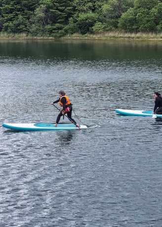 A stand up paddle board coach demonstrating to a student