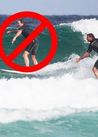 A surfer dropping in on another surfer with at red circle with a line drawn through it.