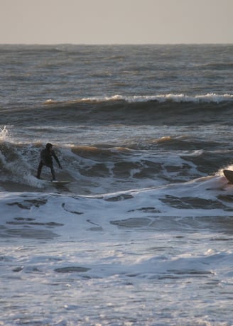 Two surfers riding towards each other in wintery sunshine