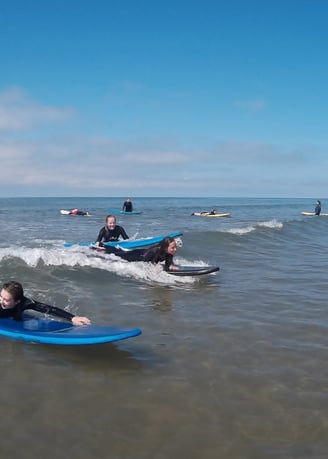 Two surfers paddling for a wave during Ysgol Tywyn activities day.