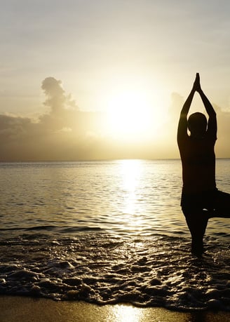 A yogi in tree pose standing in knee deep sea water