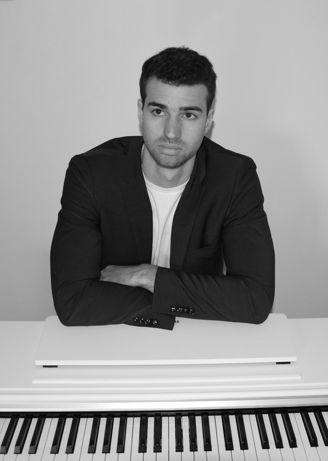 a man in a suit and tie sitting at a piano