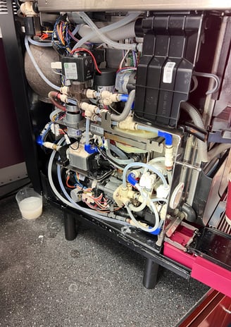 Internal components and valves exposed during super-automatic espresso machine repair