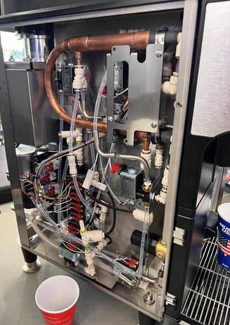 Inside view of a BUNN coffee machine showing copper pipes and valve system.