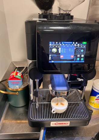 La Cimbali super-automatic espresso machine preparing cappuccino with milk jug and organic milk near
