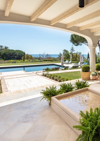 View from the shaded porch across the pool, with the Mediterranean Sea visible in the background.