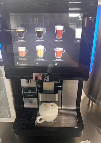 Schaerer machine preparing a cappuccino with milk froth in a ceramic cup.