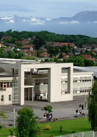 lycee jean monnet annemasse, a large building with a lot of trees and mountains in the background