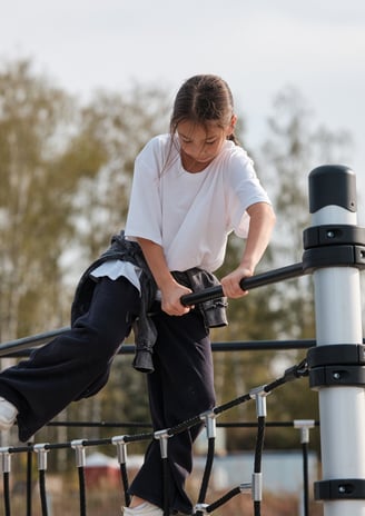 Fille grimpant sur une structure Kenguru Pro Kids Active Play en extérieur.