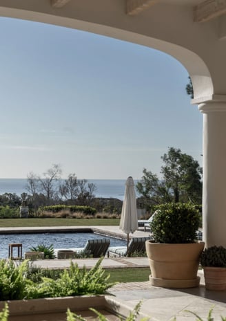 View from the shaded porch across the pool, with the Mediterranean Sea visible in the background.