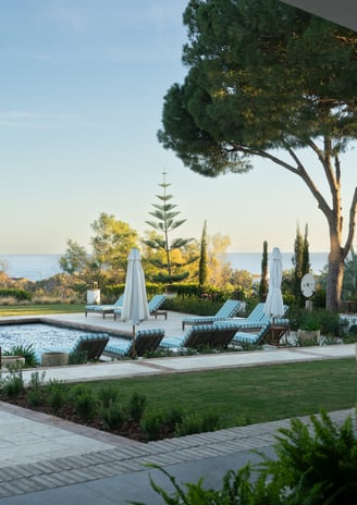 View from the shaded porch across the pool, with the Mediterranean Sea visible in the background.