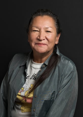 a female Native American with long hair and necklace smiling