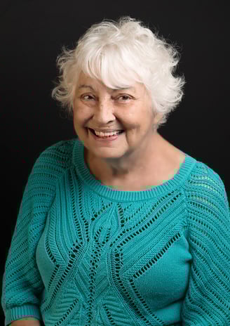 a woman with white hair and a blue sweater with big smile